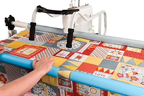 Person using longarm quilting machine on colorful quilt.