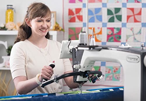 Woman using a quilting machine with colorful quilts in the background.